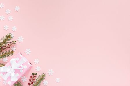 Holiday background , pink gift boxes in polka dots with white ribbon and bow and spruce branches on a pink background with snowflakes , flat lay, top viewの写真素材