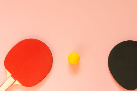 Black and red tennis  rackets and orange ball isolated on a pink background, sport equipment for table tennisの写真素材