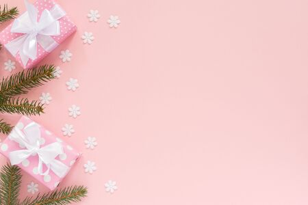 Holiday background , pink gift boxes in polka dots with white ribbon and bow and spruce branches on a pink background with snowflakes , flat lay, top viewの写真素材