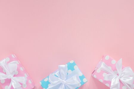 Holiday background , pink and blue gift boxes in polka dots with white ribbon and bow on a pink background , flat lay, top view, birthday or valentines dayの写真素材