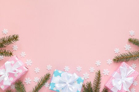 Holiday background , pink and blue gift boxes in polka dots with white ribbon and bow and spruce branches on a pink background with snowflakes , flat lay, top viewの写真素材