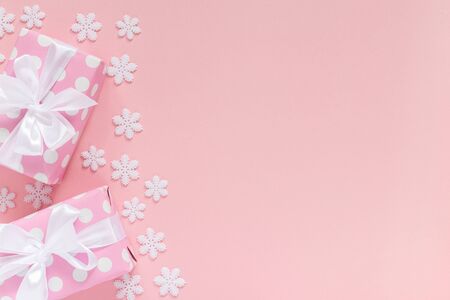 Holiday background , pink gift boxes in polka dots with white ribbon and bow on a pink background with snowflakes , flat lay, top viewの写真素材