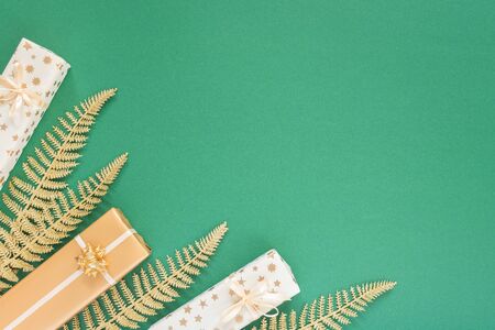 Festive green background with gold decoration , background with glitter shiny golden fern leaves and gift boxes , flat lay, top view, copy spaceの写真素材
