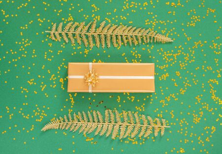 Festive background with decorations , bright shiny golden fern leaves and gift boxes on a green background with glitter gold stars, flat lay, top view, copy spaceの写真素材