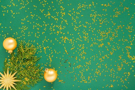 Festive background with decorations , bright gold star and christmas balls on a green background with glitter gold stars, flat lay, top view, copy spaceの写真素材