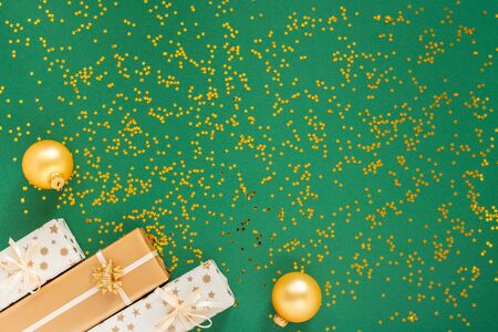 Festive background with decorations , gift boxes and christmas balls on a green background with glitter gold stars, flat lay, top view, copy spaceの写真素材