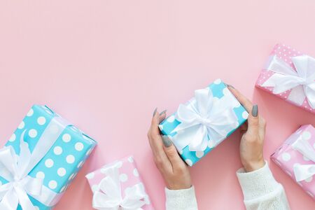 Girl holds gift box, pink and blue gift boxes in polka dots with white ribbon and bow on a pink background , flat lay, top view, birthday or valentines dayの写真素材