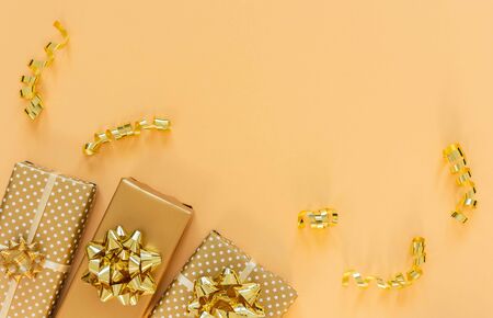 Holiday background in gold colors, gift boxes with shiny bows and with glitter ribbons serpentine on a gold background, flat lay, top view, copy spaceの写真素材