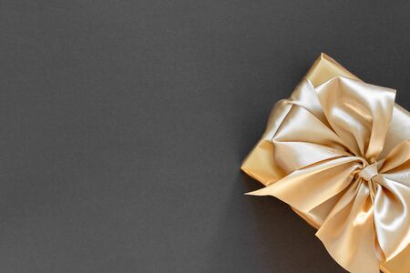 Festive background with gold gift, box with gold ribbon and bow on black background, flat lay, top view,copy spaceの写真素材