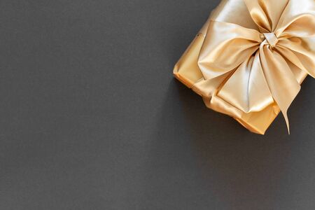 Festive background with gold gift, box with gold ribbon and bow on black background, flat lay, top view,copy spaceの写真素材