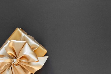 Festive background with gold gift, box with gold ribbon and bow on black background, flat lay, top view,copy spaceの写真素材