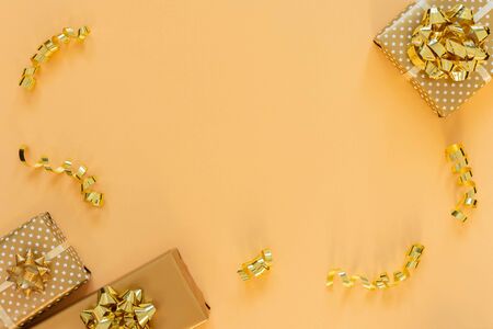 Holiday background in gold colors, gift boxes with shiny bows and with glitter ribbons serpentine on a gold background, flat lay, top view, copy spaceの写真素材