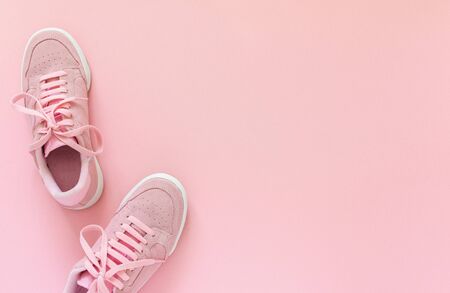 Pink nubuck sneakers isolated on a pink background, seasonal shoes for walking and sports, top viewの写真素材