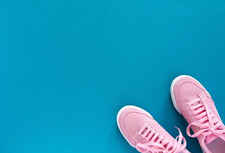 Pink nubuck sneakers isolated on a turquoise blue background, seasonal shoes for walking and sports, top viewの写真素材