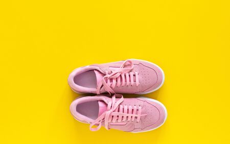 Pink nubuck sneakers isolated on a yellow background, seasonal shoes for walking and sports, top viewの写真素材