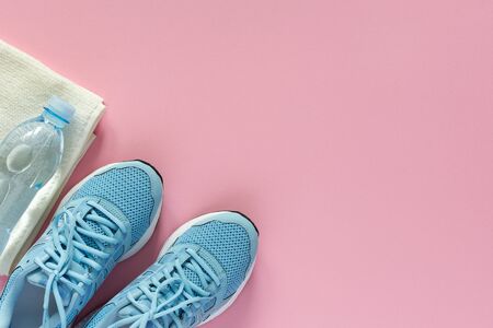 Blue sneakers and a towel with water on a pink background, playing sports or fitness, top view, healthy sport lifestyle conceptの写真素材