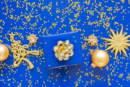 Gift boxes with a golden bow and fir tree with Christmas balls on  blueの写真素材