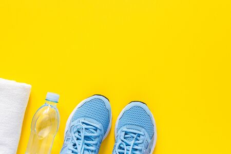 Blue sneakers and a towel with water on a yellow background, playing sports or fitness, top view, healthy sport lifestyle conceptの写真素材