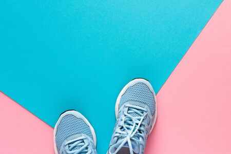Blue sneakers isolated on pink and blue background, seasonal shoes for walking and sports, copy space, top viewの写真素材