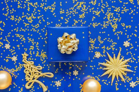 Gift boxes with a golden bow and fir tree with Christmas balls on  blueの写真素材