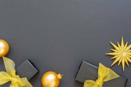 Festive background with gold decorations , shiny golden star and gift boxes and christmas balls on a black background , flat lay, top view, copy spaceの写真素材