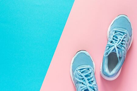 Blue sneakers isolated on pink and blue background, seasonal shoes for walking and sports, copy space, top viewの写真素材