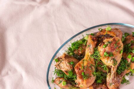 Baked chicken drumsticks with rosemary, spices, onions and dill on a pink tablecloth, top viewの写真素材