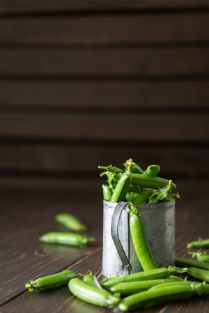 Fresh young green peas in pods in a tin mug, ripe organic vegetablesの写真素材