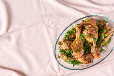 Baked chicken drumsticks with rosemary, spices, onions and dill on a pink tablecloth, top viewの写真素材