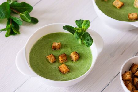 Delicious fresh cream soup of young peas and mint with croutons made of white bread, healthy foodの写真素材
