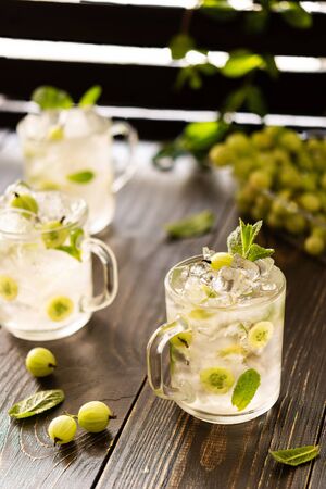 Cold summer drink with green gooseberries and mint, lemonade with iceの写真素材