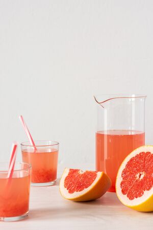 Summer refreshing grapefruit drink, jug and glasses with grapefruit pulp and juice and strawsの写真素材