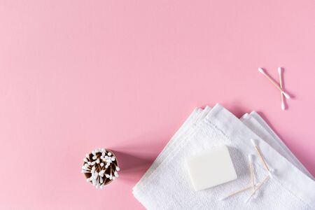 White towel with soap and wooden cotton swabs in an eco cup on a pink background, bath spa accessoriesの写真素材