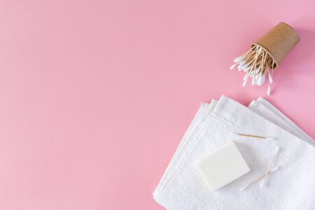 White towel with soap and wooden cotton swabs in an eco cup on a pink background, bath spa accessoriesの写真素材