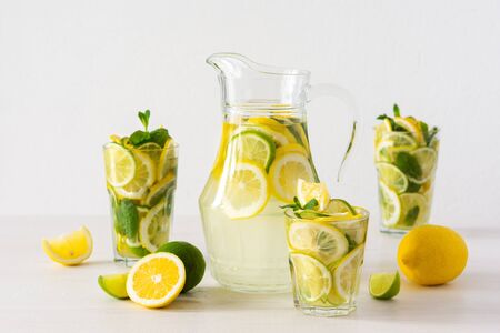 Summer refreshing drink of lemon, lime and mint, jug with lemonade and glasses and citrus slicesの写真素材