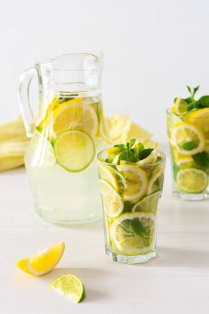Summer refreshing drink of lemon, lime and mint, jug with lemonade and glasses and citrus slicesの写真素材
