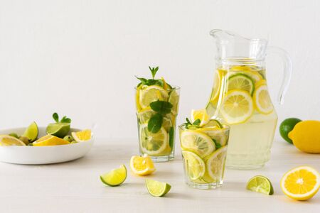 Summer refreshing drink of lemon, lime and mint, jug with lemonade and glasses and citrus slicesの写真素材