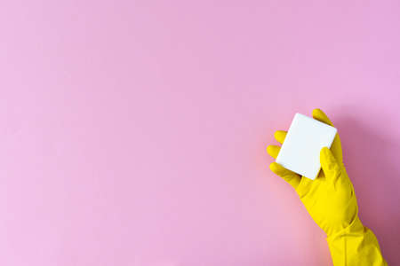 Hand in a yellow rubber glove with soap on a pink backgroundの写真素材