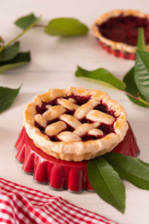 Open pie from shortcrust pastry with cherries and raspberries, a pie with a serviette on a white backgroundの写真素材