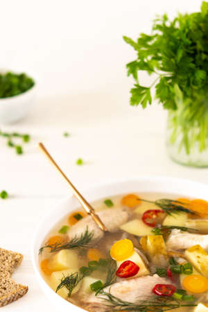 Chicken soup with fresh vegetables, chicken wings broth and young potatoes with onions and carrots, chopped green onions and parsleyの写真素材