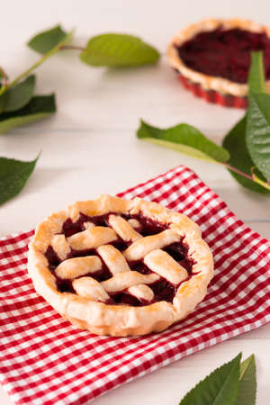 Open pie from shortcrust pastry with cherries and raspberries, a pie with a serviette on a white backgroundの写真素材