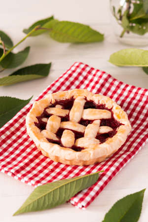 Open pie from shortcrust pastry with cherries and raspberries, a pie with a serviette on a white backgroundの写真素材