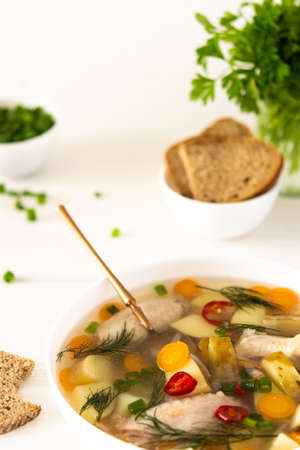 Chicken soup with fresh vegetables, chicken wings broth and young potatoes with onions and carrots, chopped green onions and parsleyの写真素材