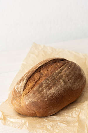 Loaf of homemade bread from wheat and seeds on parchment paperの写真素材