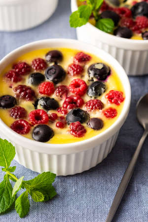 Delicious clafoutis made from white yogurt and berries, raspberries and blueberries, clafoutis in portioned bowls on the tableの写真素材