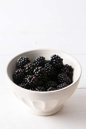 Blackberries close-up in bowls on a white background, ripe juicy berriesの写真素材