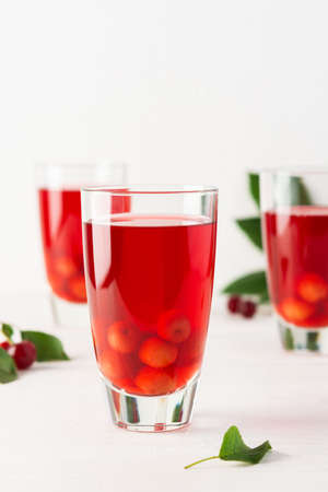 Summer delicious refreshing cherry compote with pulp and with ice in glasses on a white backgroundの写真素材