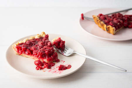 Cherry clafoutis on white background, plates with a portion of the pie and spoonsの写真素材