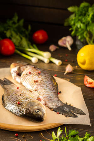 Fresh carassius on the board, river fish crucian carp with spices ready for frying or roasting in the ovenの写真素材