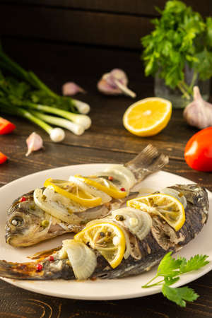 Baked carassius with lemon and spices in foil in the oven, cooked river fish crucian carpの写真素材